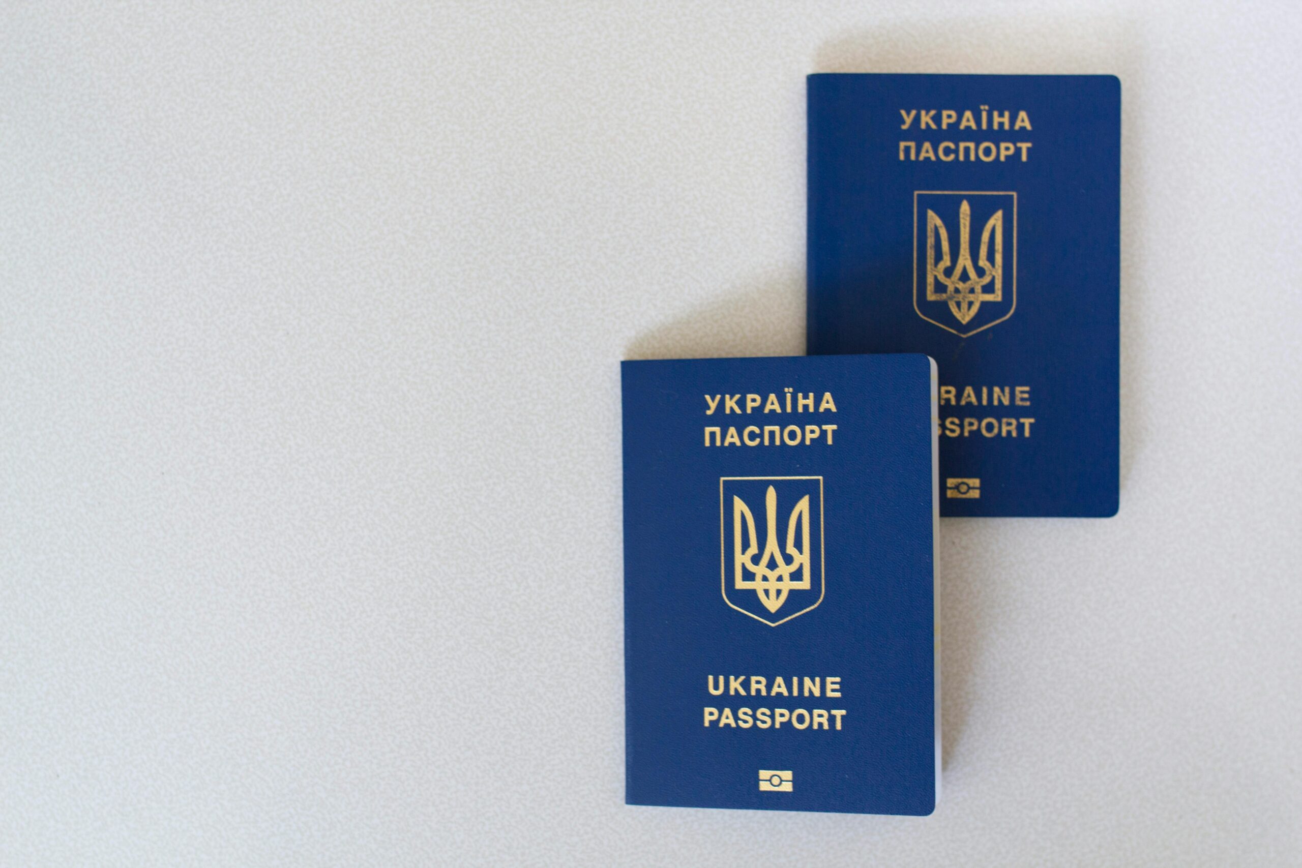 Two blue Ukrainian passports placed on a white surface, close-up view.