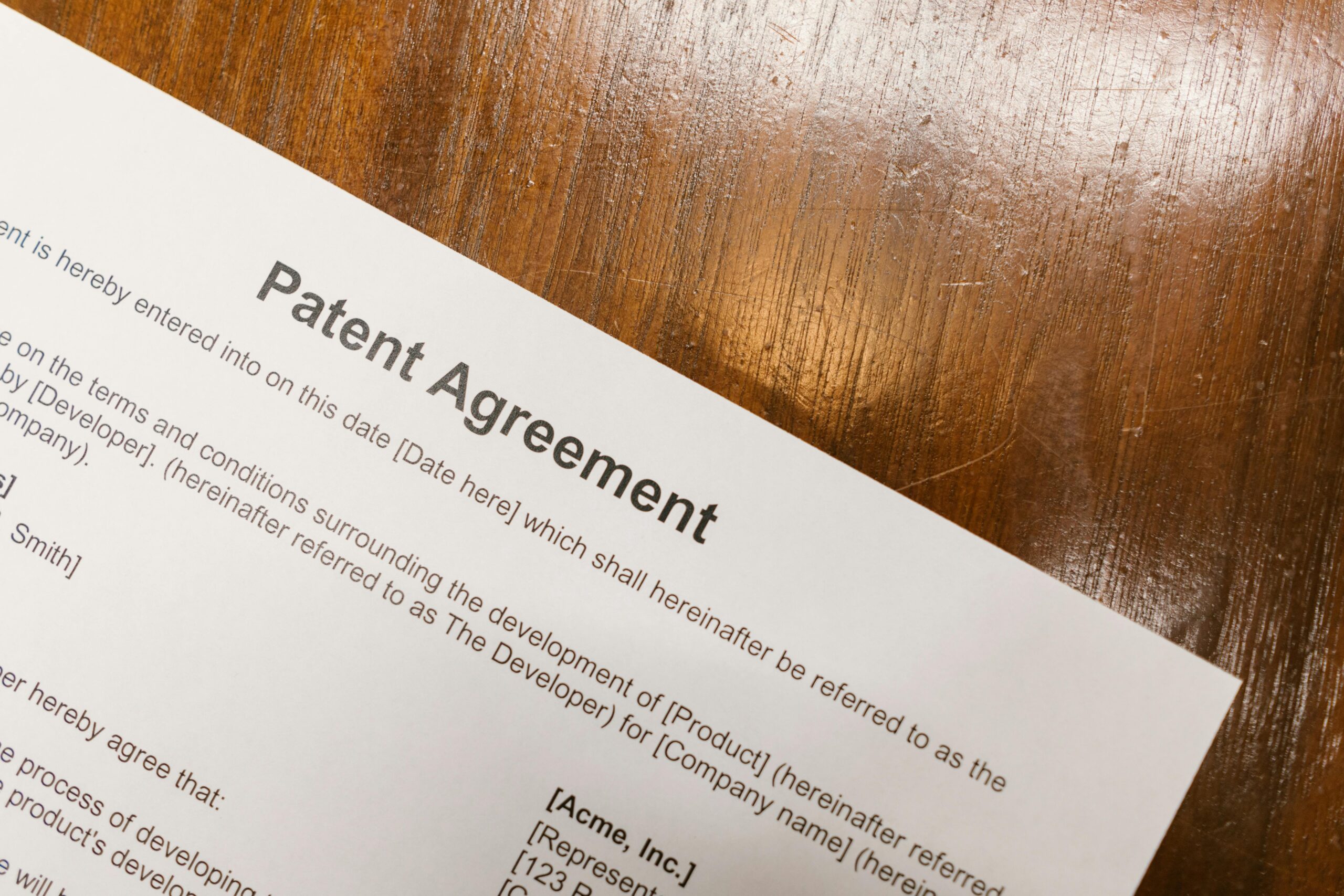 Detailed close-up of a patent agreement document on a polished wooden table.