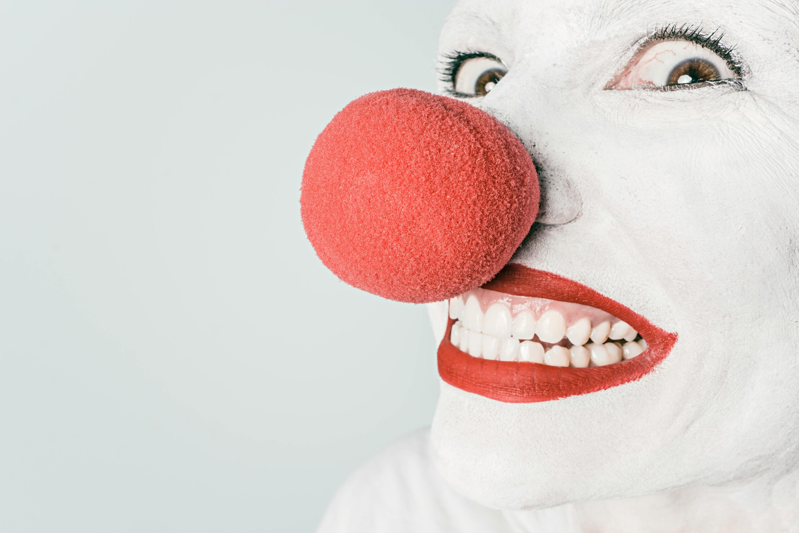 Bright close-up of a clown's face with red nose and makeup, showcasing humor and joy.