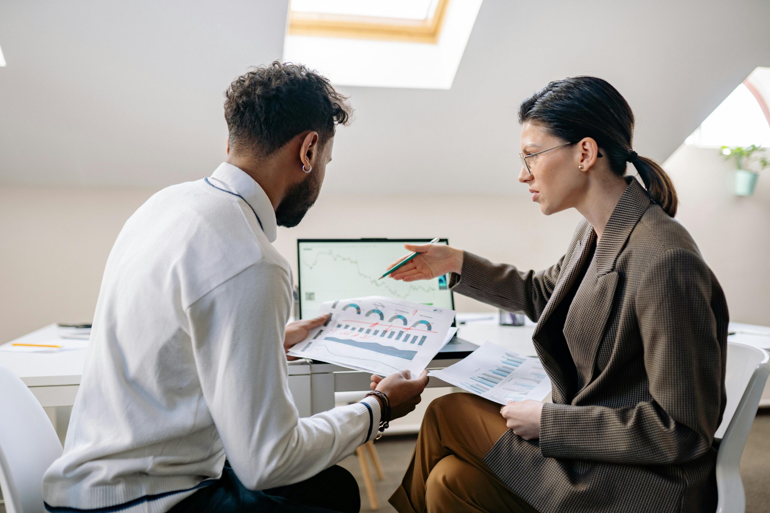 Colleagues in an office setting reviewing charts and graphs for a business presentation.