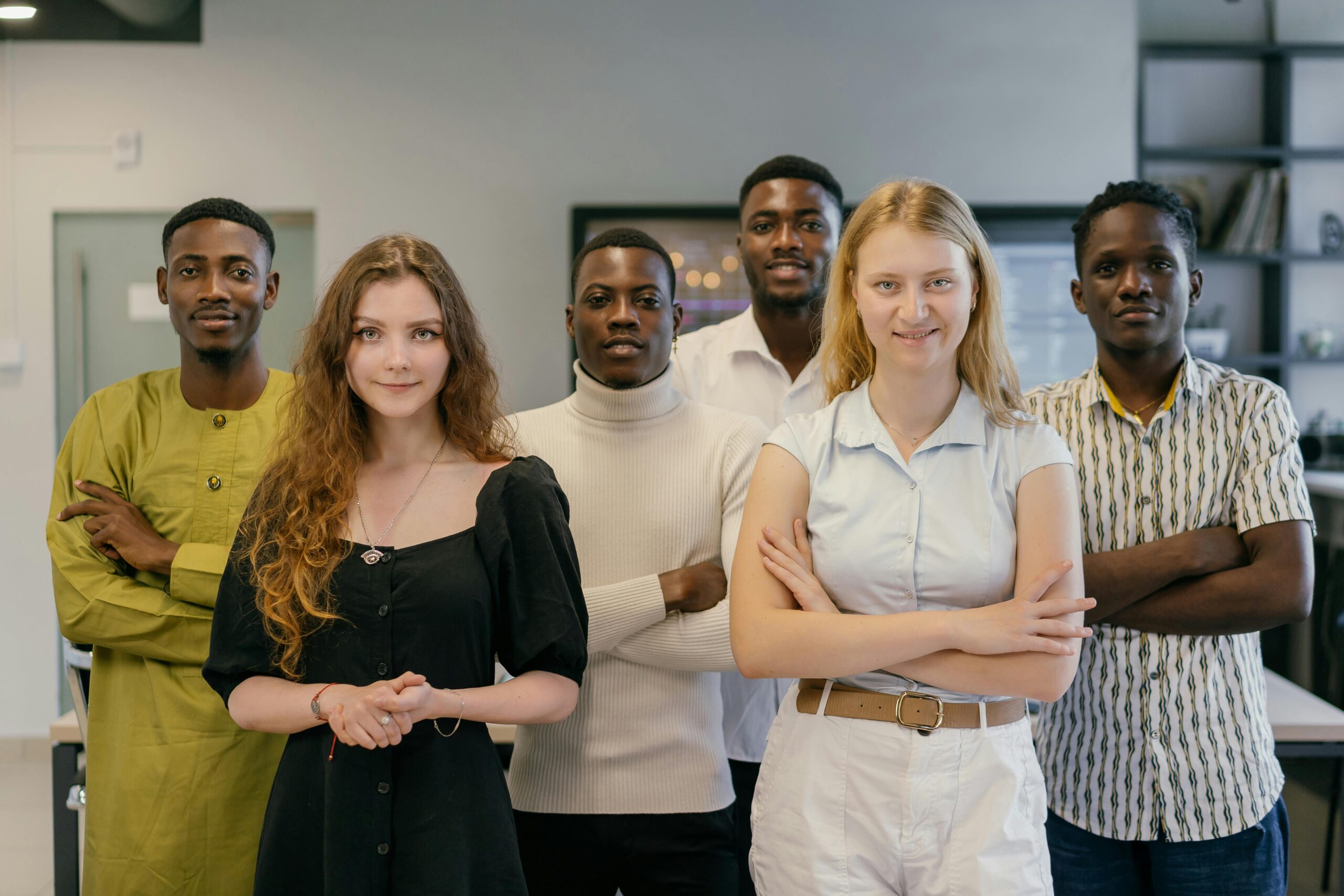 A diverse group of young professionals posing confidently in a modern office setting.