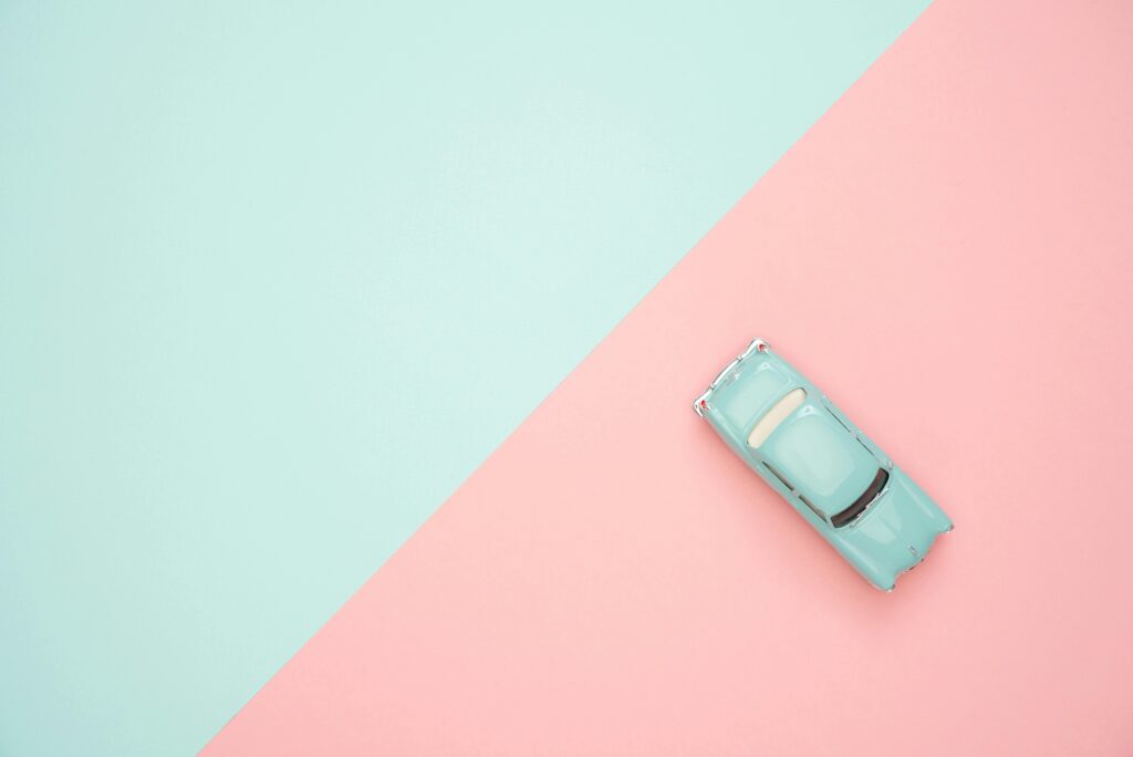 Toy car on a pastel pink and blue background, representing simplicity and retro design.