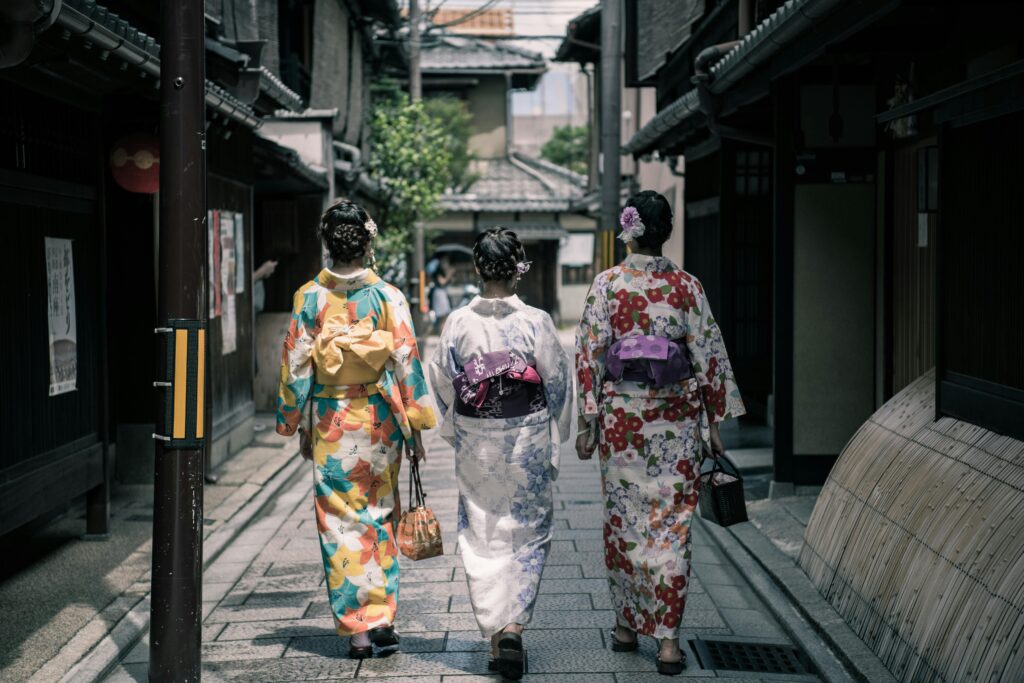 Three women in colorful kimonos walking through a traditional street in Kyoto, Japan.