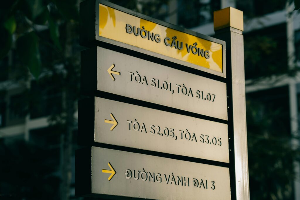 Vietnamese directional street sign with arrows in an urban setting.