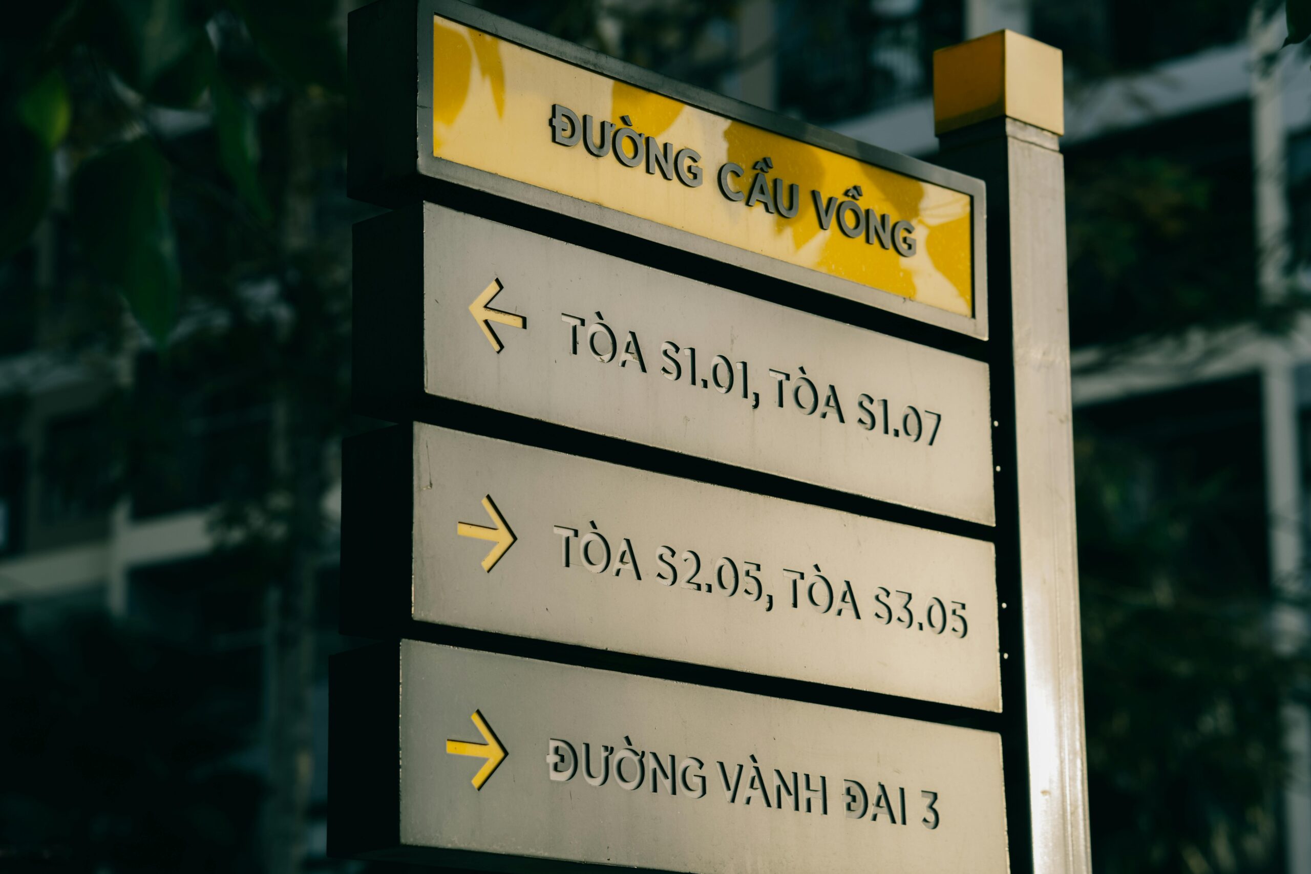 Vietnamese directional street sign with arrows in an urban setting.