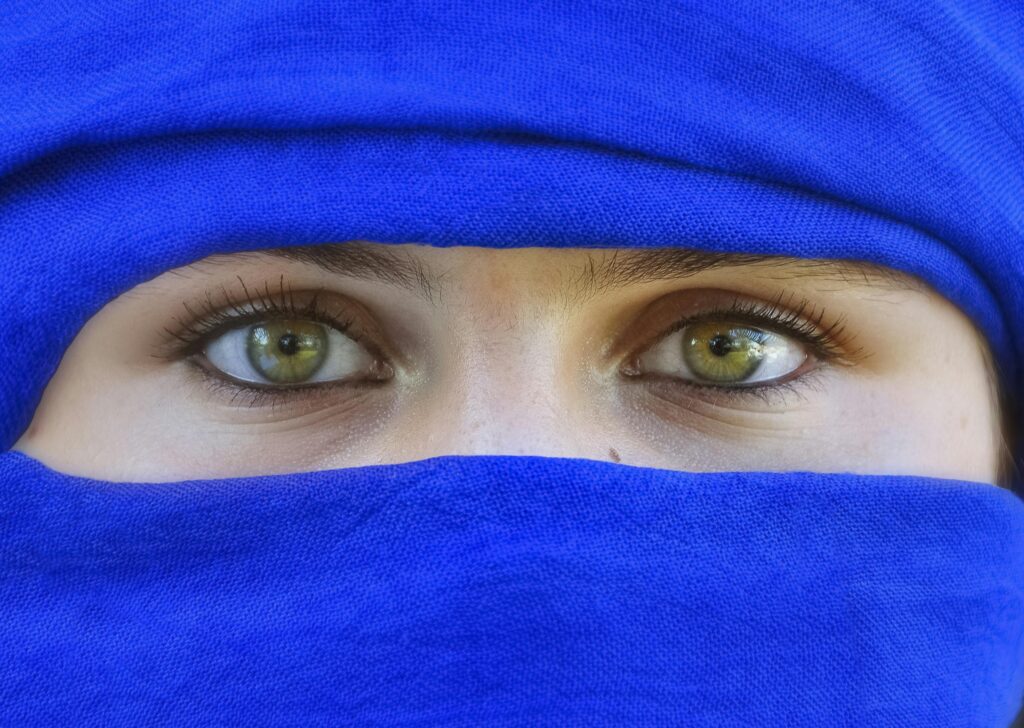 A striking close-up of a woman's eyes framed by a blue niqab, highlighting cultural and fashion elements.