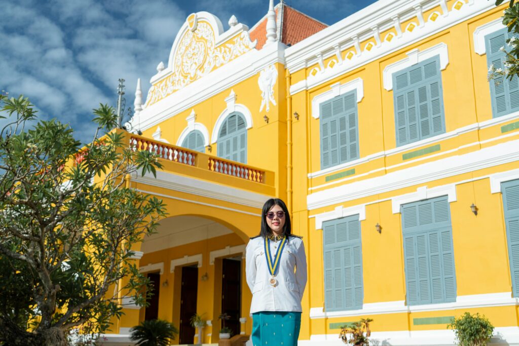 Woman poses in front of a vibrant, historic building with ornate details.