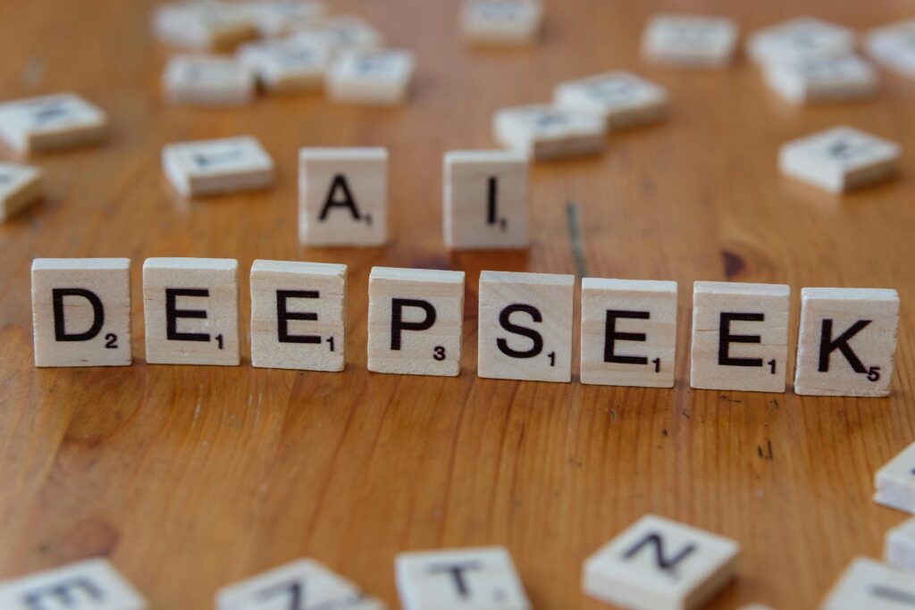 Wooden Scrabble tiles spelling 'DEEPSEEK' with 'AI' on a wooden table, illustrating AI concepts creatively.