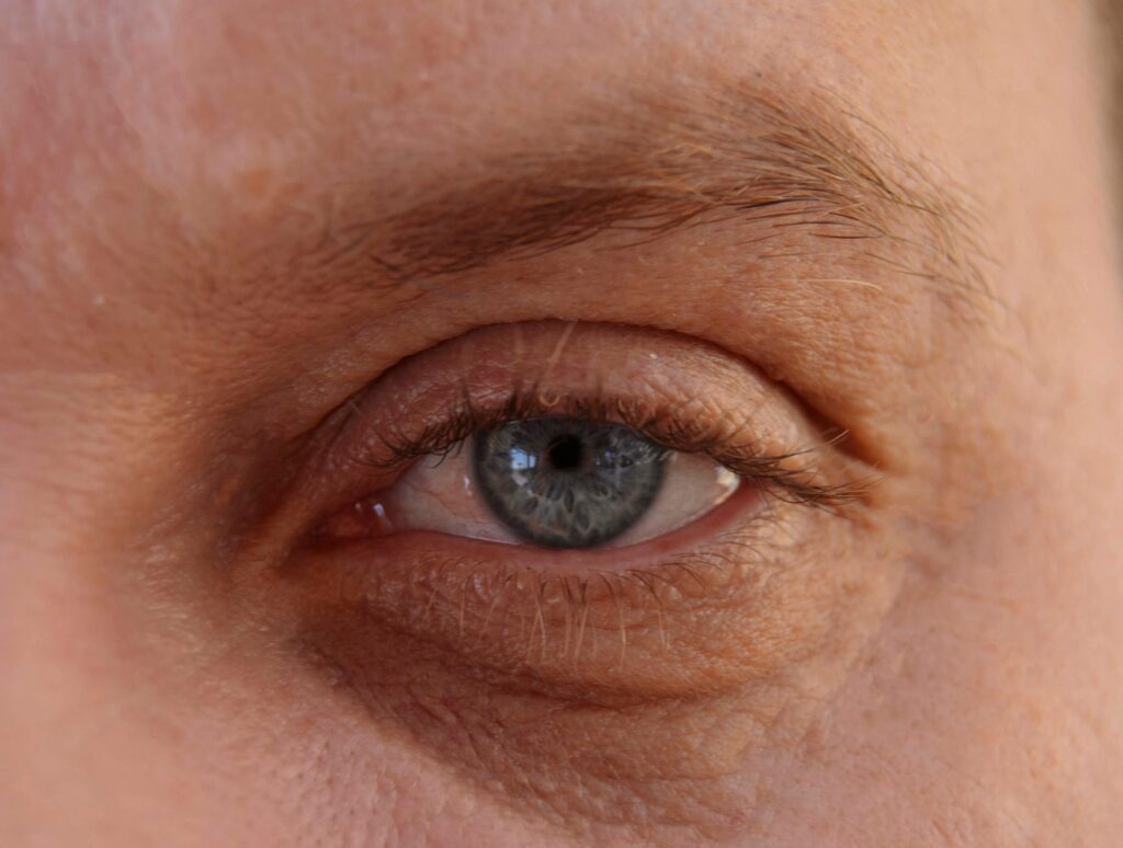 Detailed close-up of an adult human eye with blue iris and visible eyelashes.