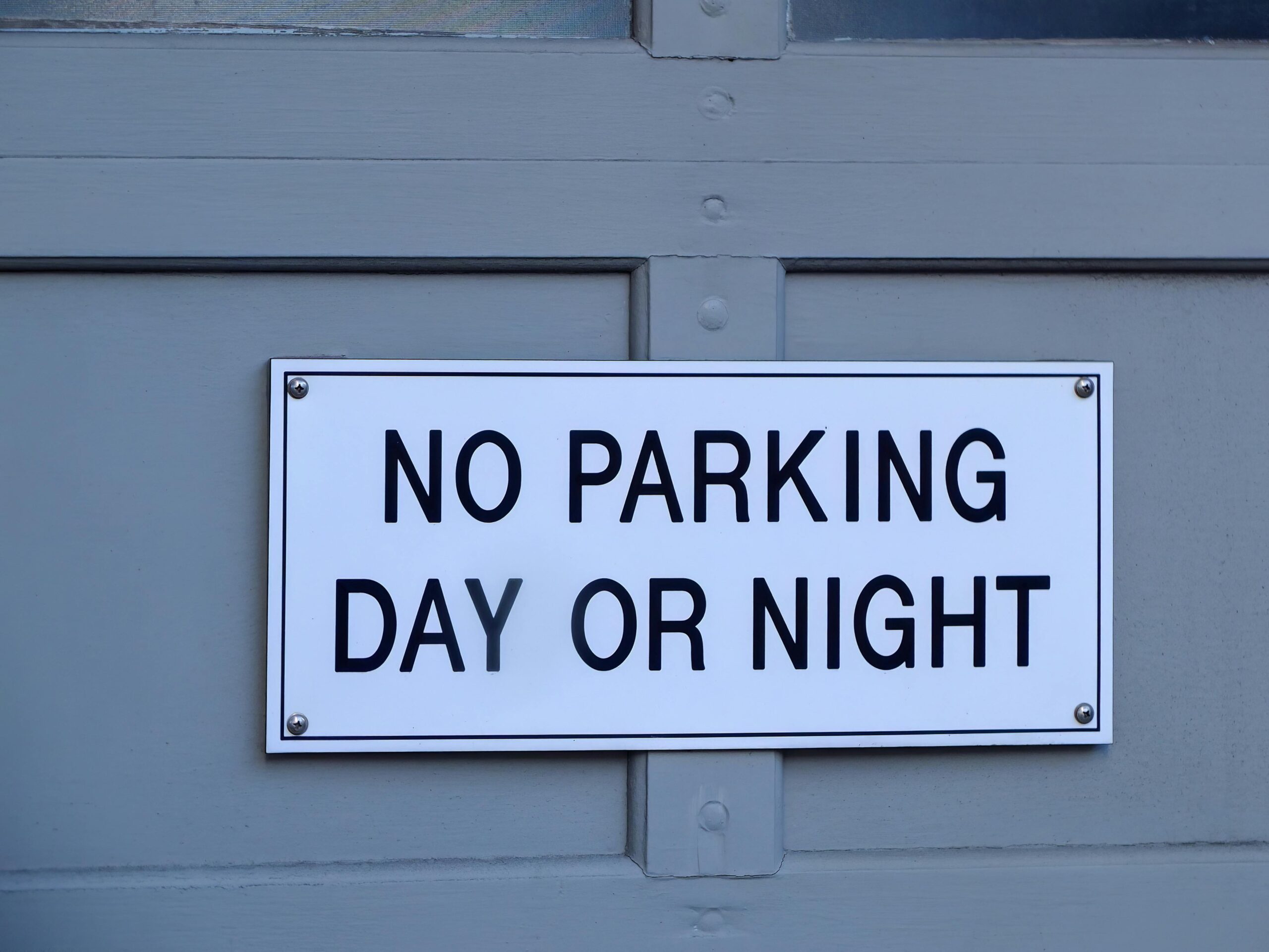 Close-up of a no parking sign mounted on a blue painted wall, emphasizing prohibition and warning.