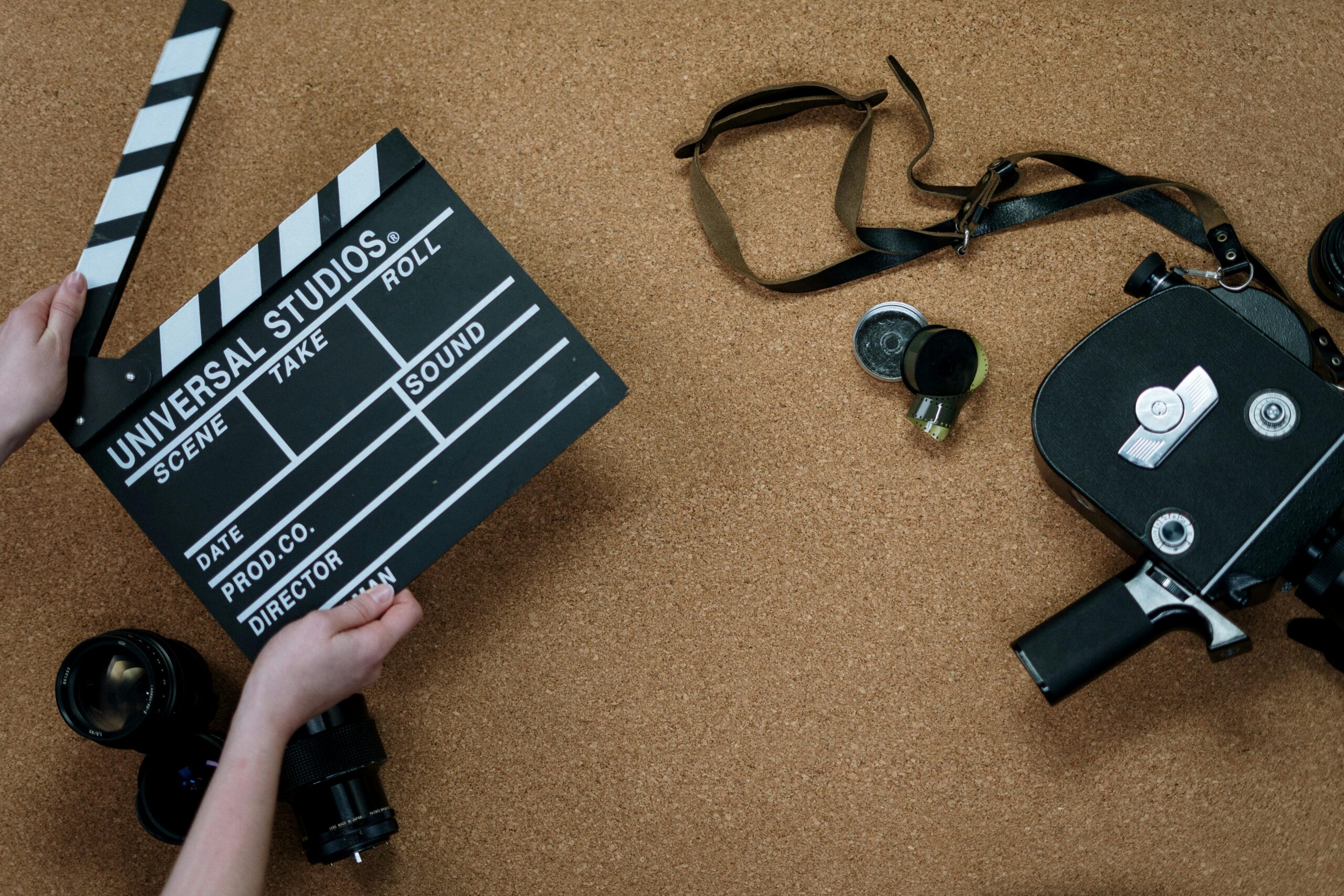 Top view of vintage film camera and clapperboard on cork background, evoking old cinema vibes.