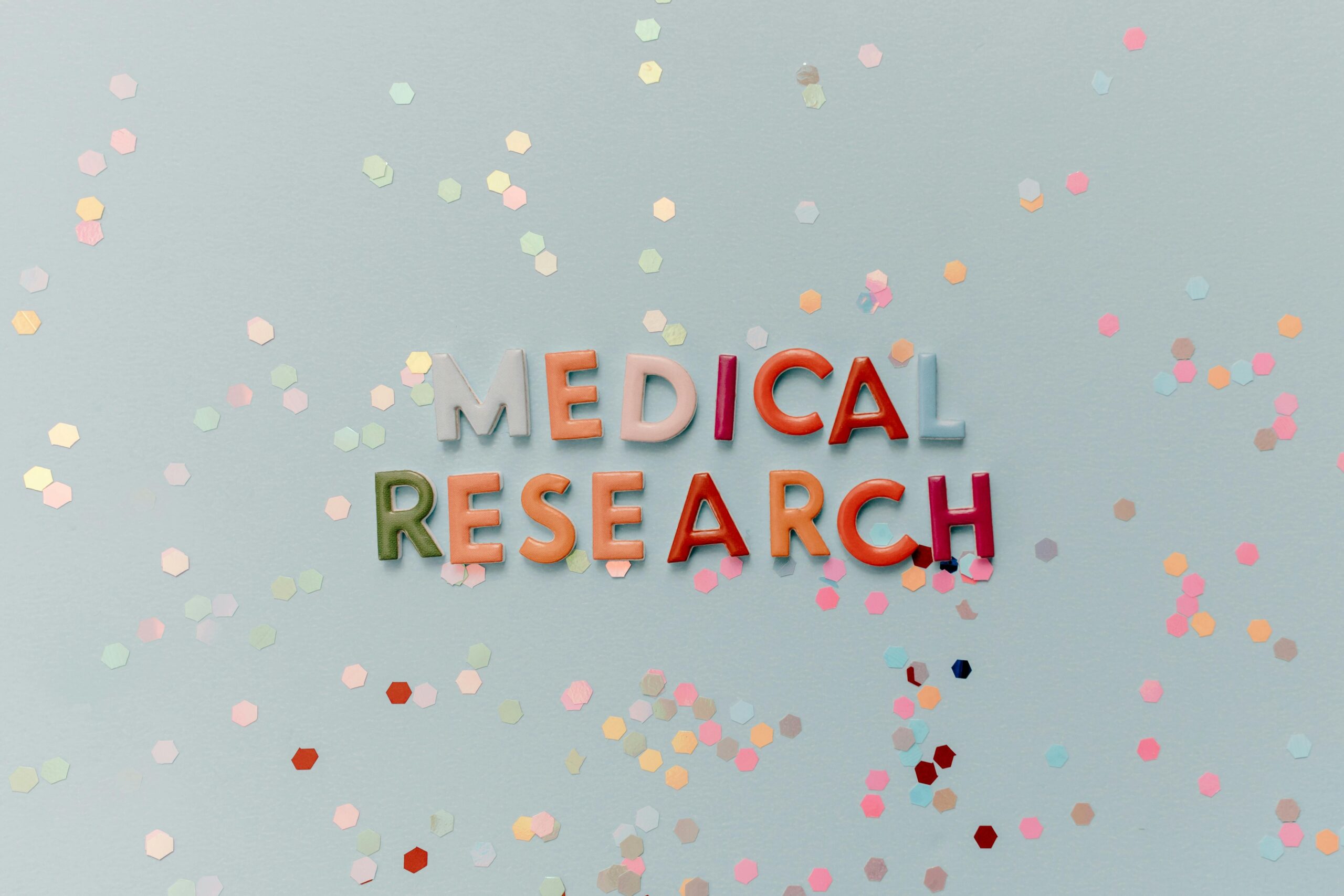 Colorful letters spell "Medical Research" against a confetti-strewn backdrop.