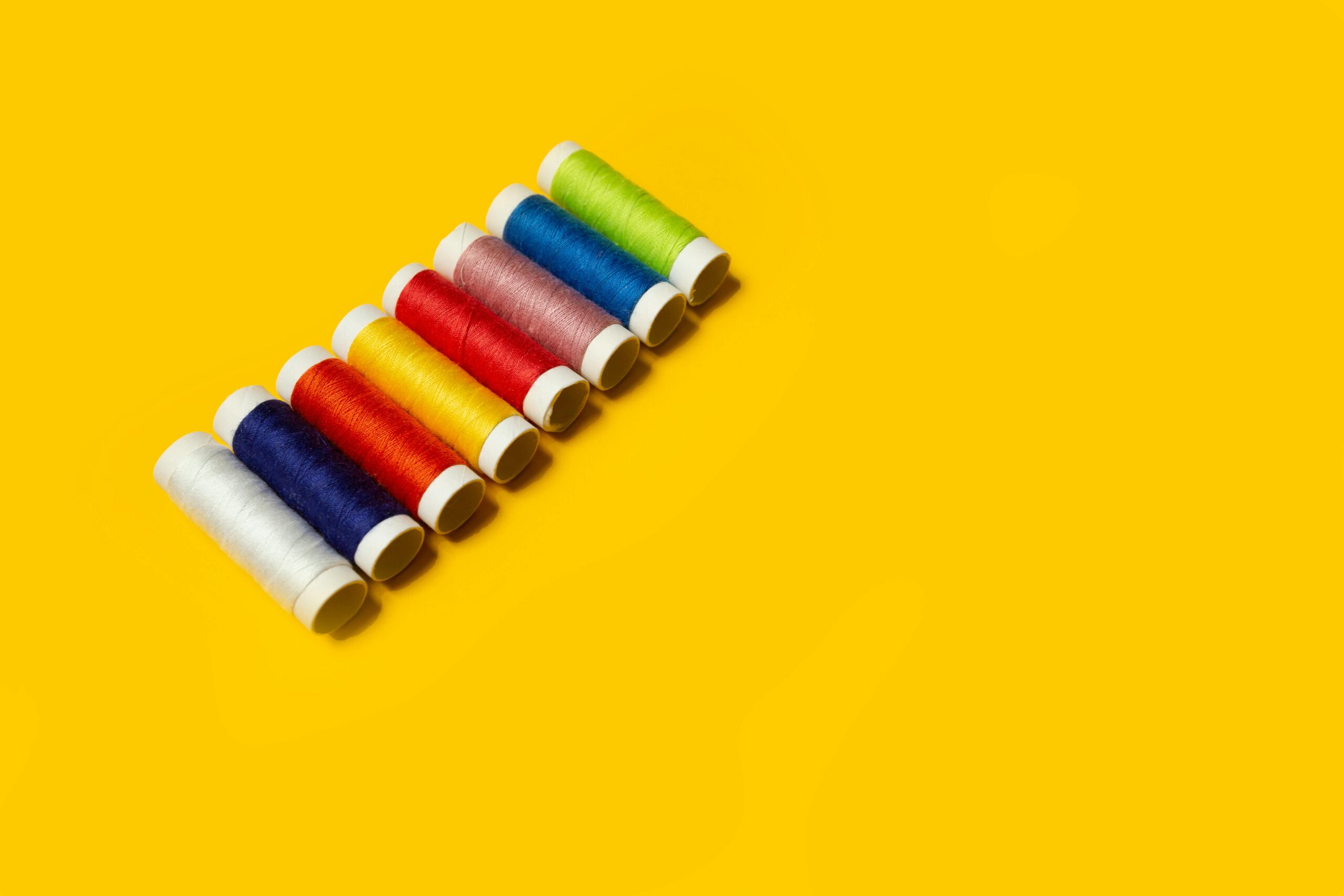 Vibrant spools of cotton thread on a yellow background, perfect for textile and sewing projects.